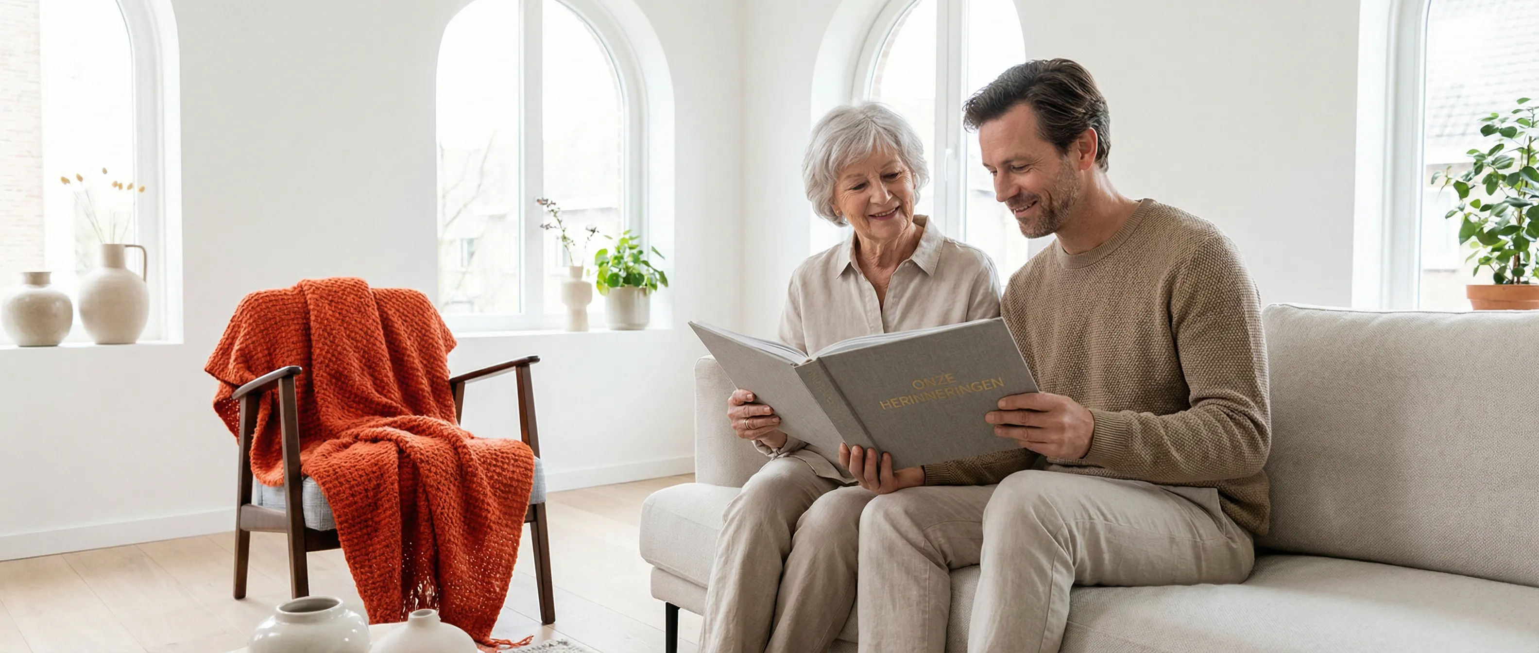 Een zoon en zijn oudere moeder bespreken de ouderlijke verhuizing in een lichte woonkamer met een fotoalbum.
